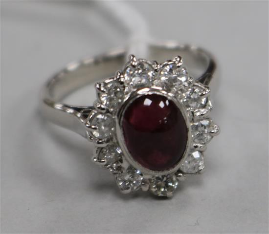 An 18ct white gold, cabochon garnet and diamond oval cluster ring, size M.